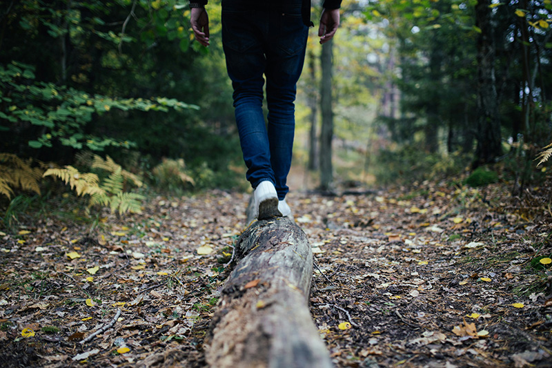 Person går på stock i skogen